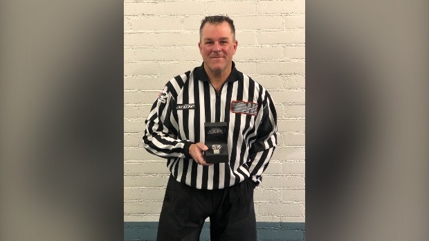 Linesman Kevin Hastings stands poses with the commemorative watch given to him to mark his 1,000th game. (Kitchener Rangers/Twitter)